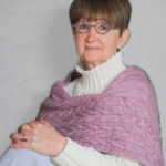 Picture of author Deanie Yasner wearing her signature round glasses with a lavender knitted wrap over a white turtleneck sweater